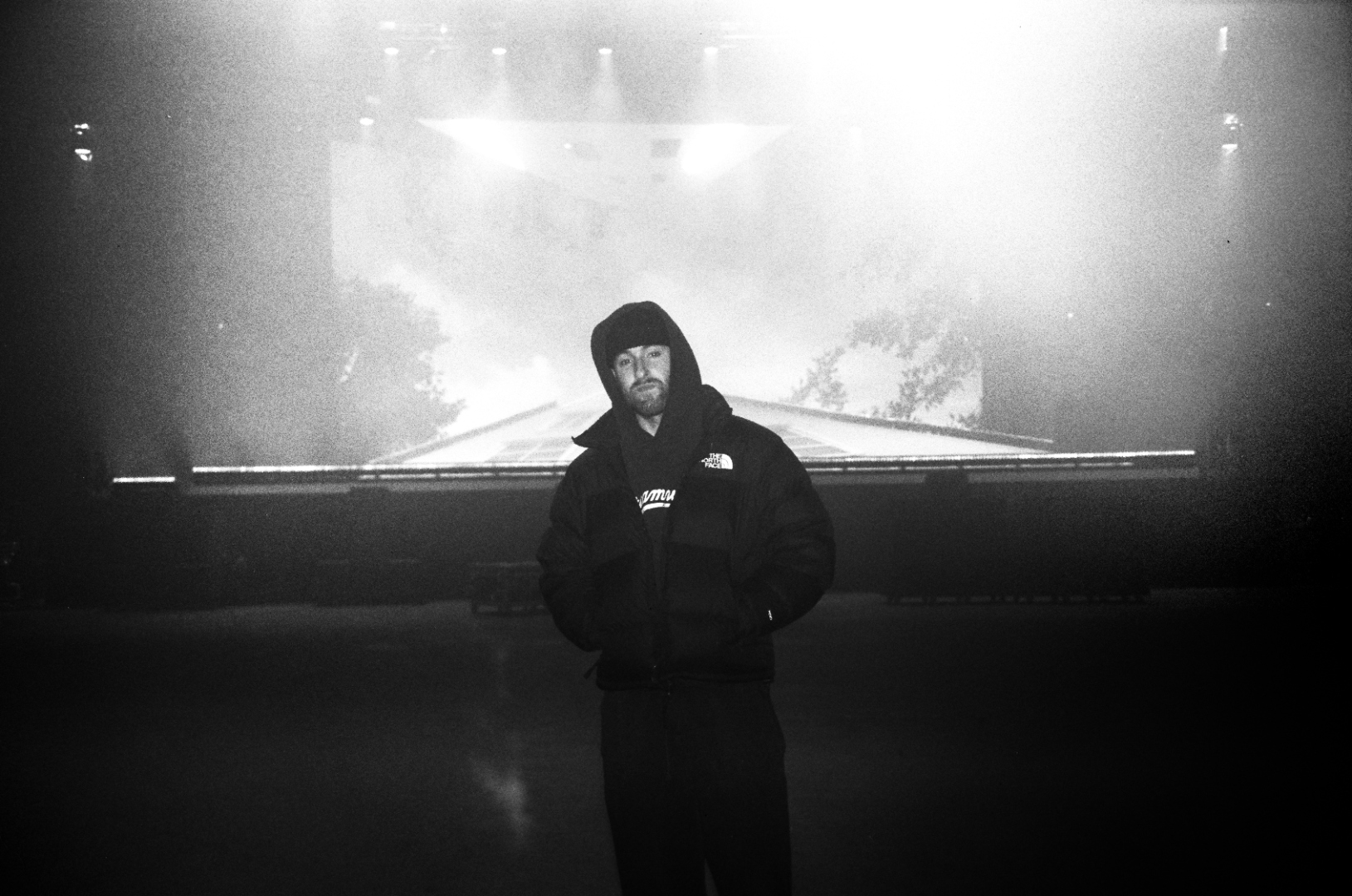 David Peters standing on an empty tour stage under a single spotlight