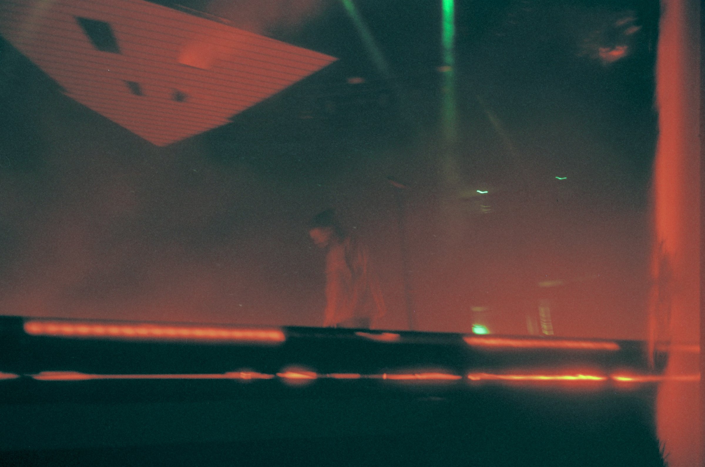 On-stage moment lit in deep red with a green laser overhead, photographed by David Peters
