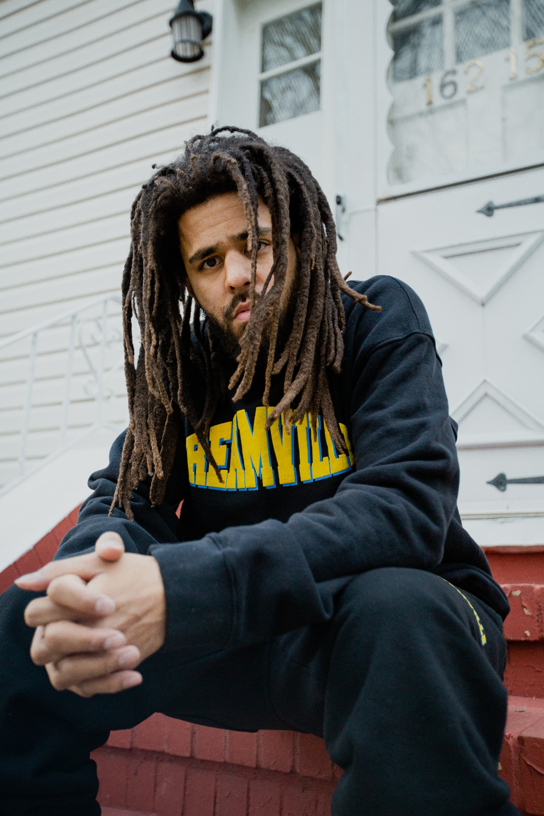 J. Cole on Fayetteville stoop in Dreamville hoodie