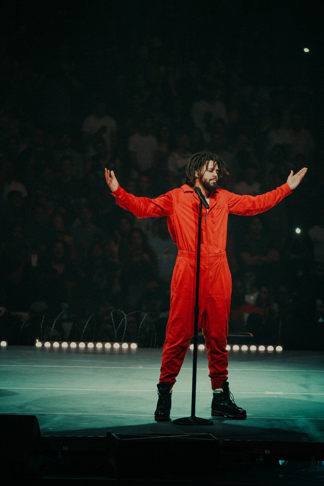 J. Cole in red jumpsuit onstage
