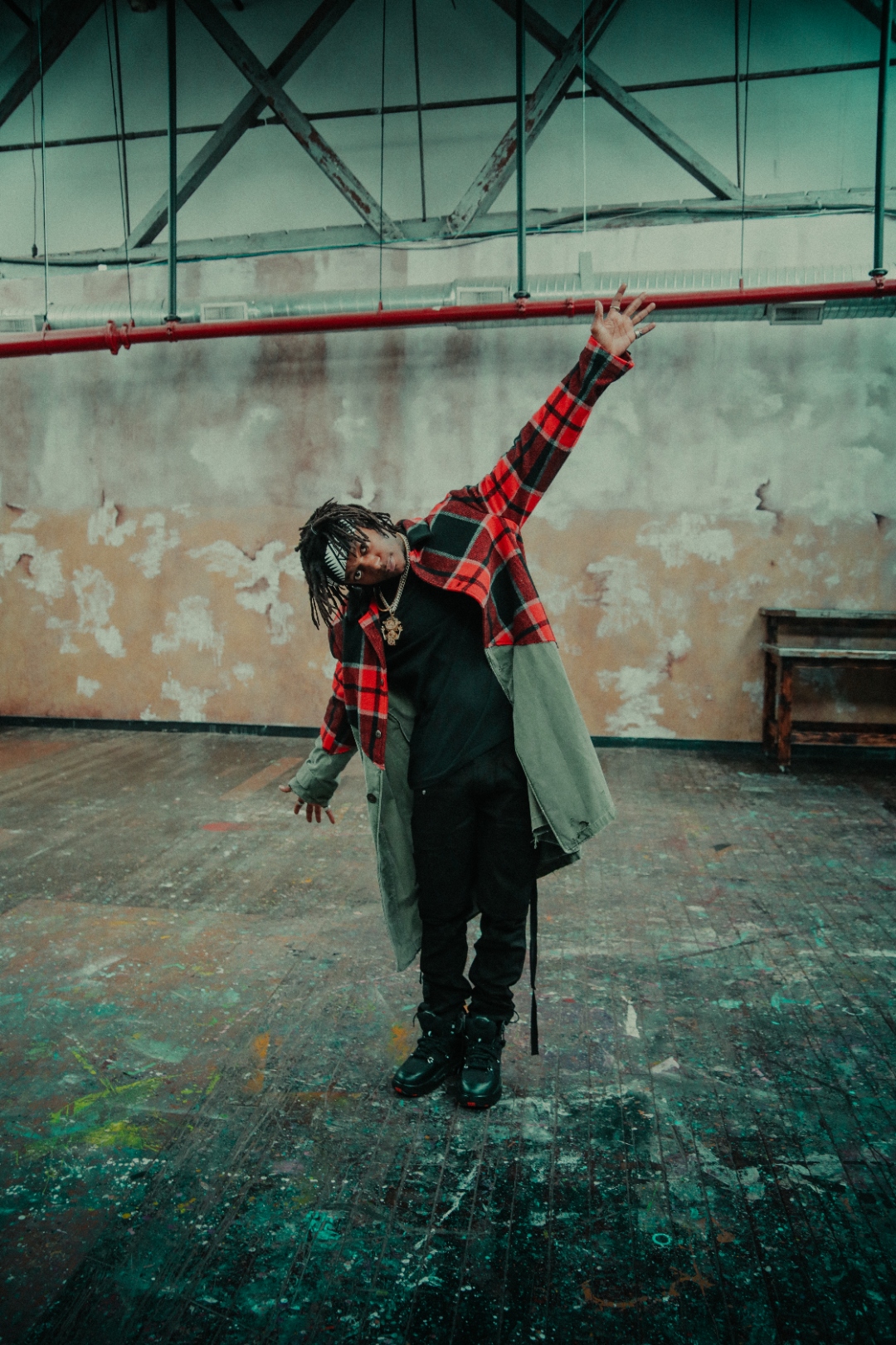 JID reaching upward in warehouse in red plaid