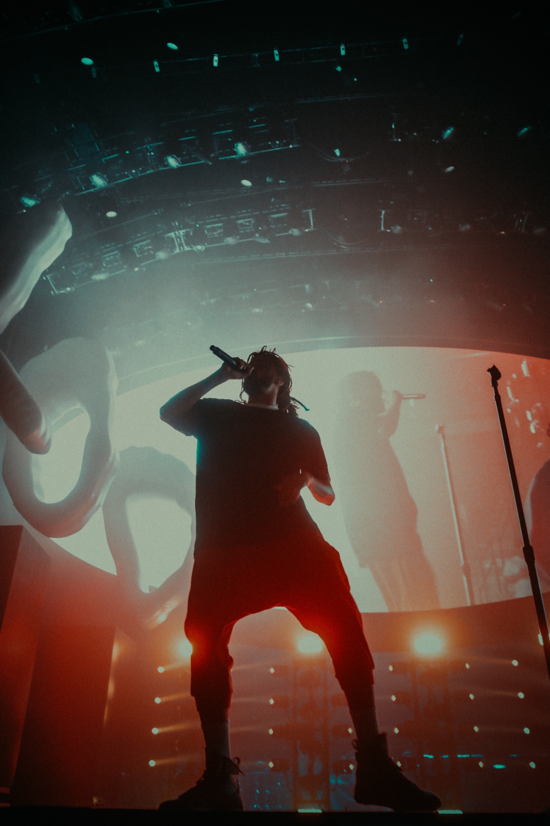 J. Cole from behind pointing mic upward
