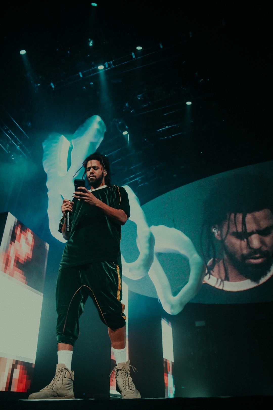J. Cole holding phone on stage