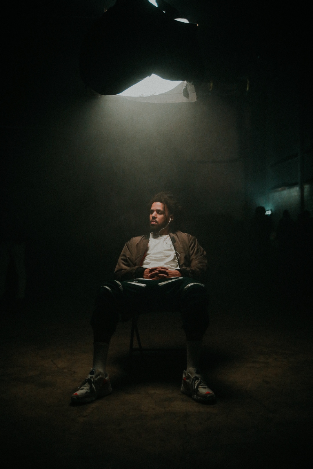J. Cole seated under single light