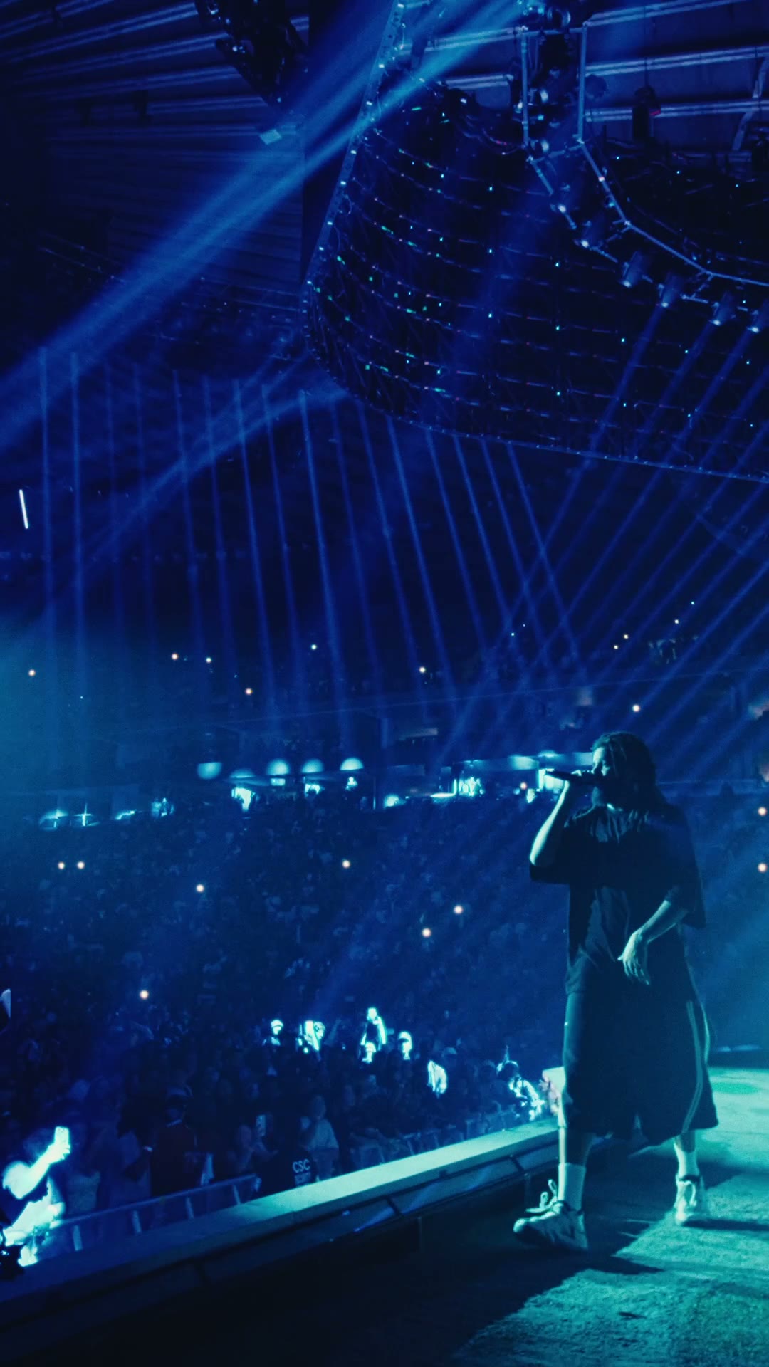 Wide arena shot with blue light beams and packed crowd